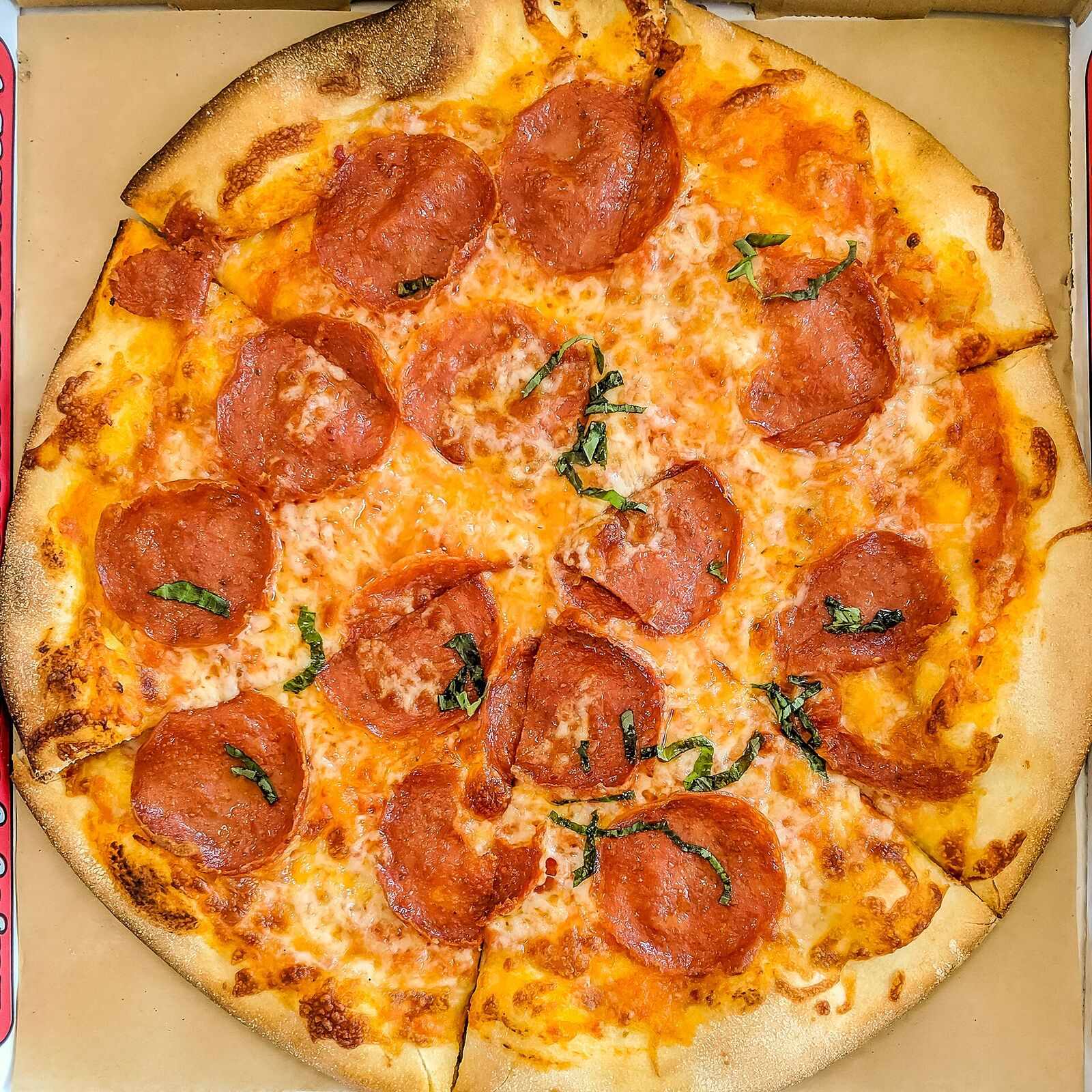 Whole pepperoni pizza seen from above, covered edge to edge in cupped pepperoni